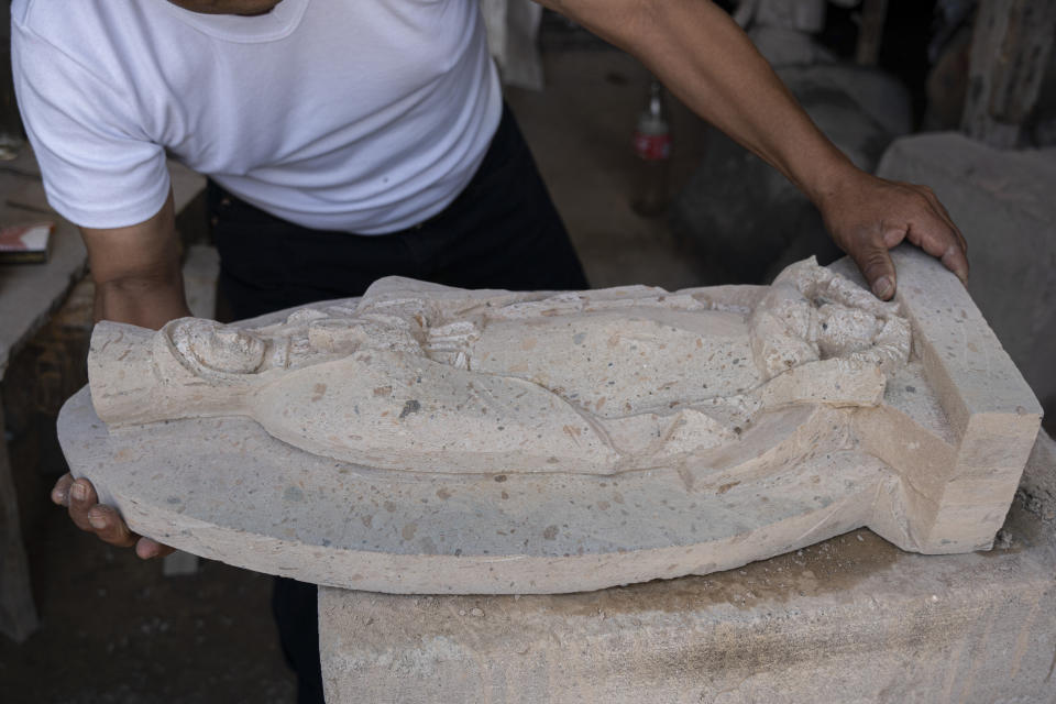 Mario Olivares shows his stone carving at the cemetery in the Mexico City borough of Chilmalhuacan, once the ancient village of Xochiaca, Sunday, July 2, 2023. Asked if the trade will survive, Olivares recited a poem carved by the artisans in the church wall: “Your art, your tradition, your culture, and the nobility of the people keeps the soul of this town alive.” (AP Photo/Aurea Del Rosario)