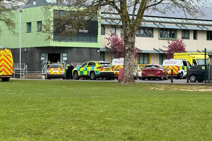 Several police and ambulance vehicles parked outside the school