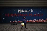 A woman, wearing a face mask to prevent the spread of the coronavirus, walks past a board promoting Christmas shopping in a commercial street in downtown Brussels, Tuesday, Dec. 1, 2020. Non-essential shops in Belgium are reopening on Tuesday in the wake of encouraging figures about declining infection rates and hospital admissions because of the coronavirus. (AP Photo/Francisco Seco)