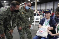 CORRECTS THAT RUSSELL IS FROM ALBANY, ORE. INSTEAD OF ALBANY, N.Y. - Pearl Harbor survivor and World War II Navy veteran David Russell, 101, of Albany, Ore., shows off his commemorative bag to two military personnel before the start of the 80th Pearl Harbor Anniversary ceremony at Joint Base Pearl Harbor-Hickam, Tuesday, Dec. 7, 2021, in Honolulu. (AP Photo/Marco Garcia)