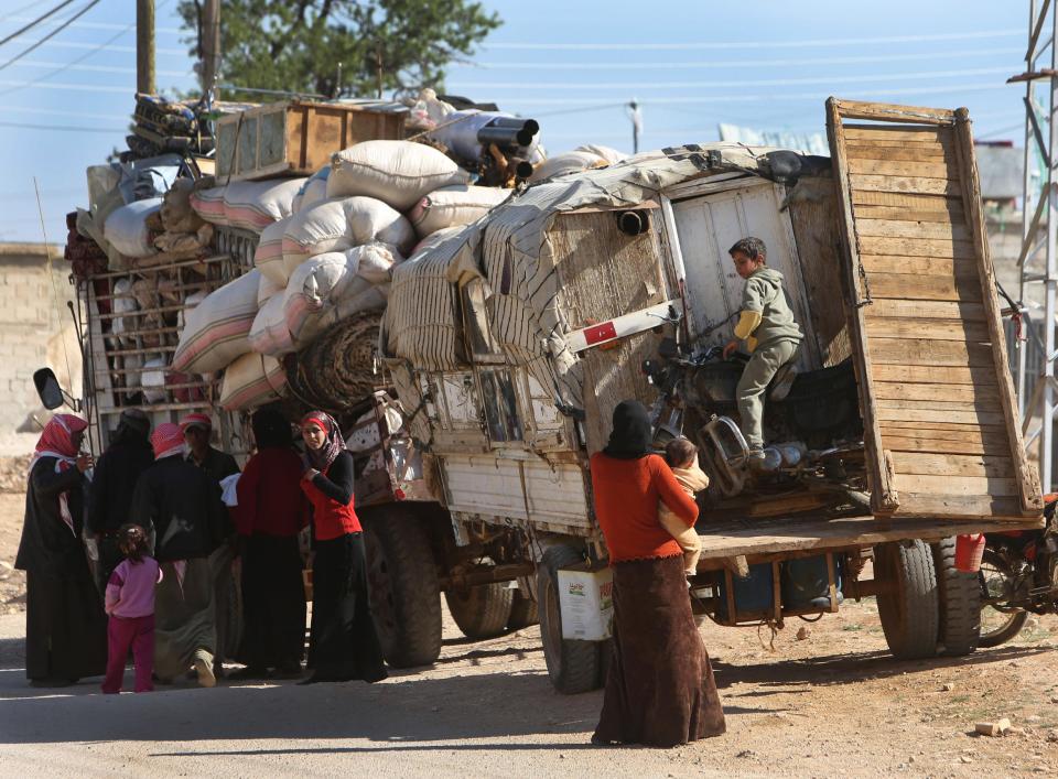 Syrian refugees who fled from the Syrian town of Rankous, stand next to trucks which carry their belongings, in Tfail village, at the Lebanese-Syrian border, eastern Lebanon, Tuesday April 22, 2014. A Lebanese convoy of soldiers, clerics and Red Cross officials delivered aid Tuesday to a remote village near the Syrian border that was bombed by Syrian government aircraft and blocked by Lebanese militants fighting alongside President Bashar Assad’s forces in the civil war next door. Hezbollah fighters have been patrolling the area on the Lebanese side and fighting has flared up inside Syria, cutting Tfail’s residents off from all sides for months. (AP Photo/Hussein Malla)