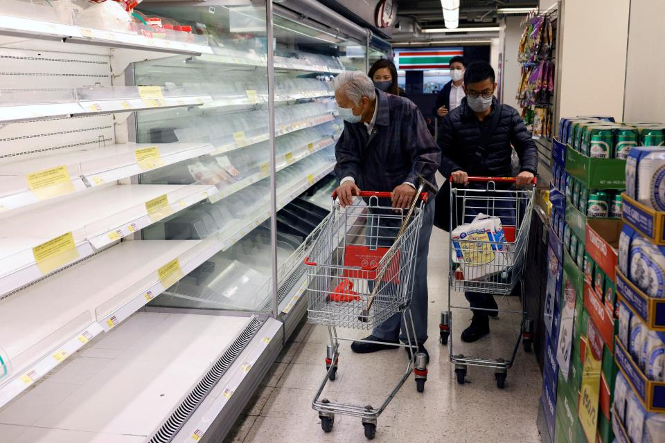 Customers wearing masks shop in front of partially empty shelves at a supermarket during the coronavirus disease (COVID-19) outbreak in Hong Kong, China February 28, 2022.