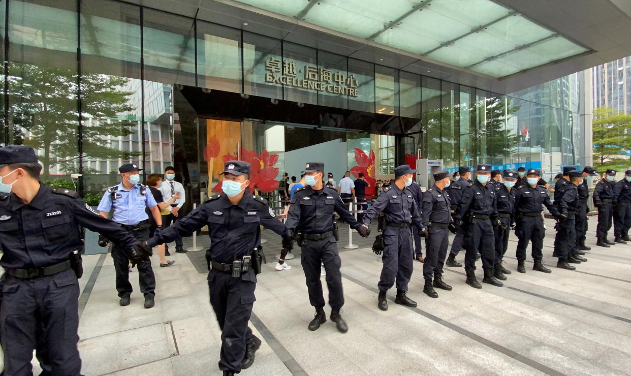 Security personnel form a human chain as they guard outside the Evergrande's headquarters, where people gathered to demand repayment of loans and financial products, in Shenzhen, Guangdong province, China September 13, 2021. REUTERS/David Kirton