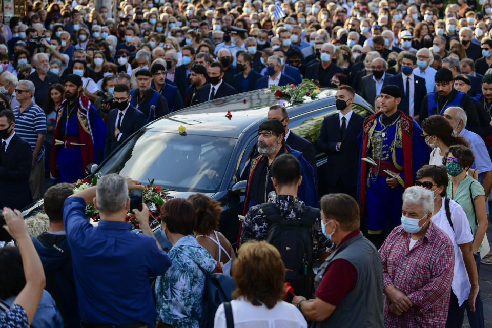 Men in traditional dress of the island of Crete and people escort a hearse, ahead of the burial of the late Greek composer, Mikis Theodorakis, in Chania Crete island, Greece, Thursday, Sept. 9 2021. Theodorakis died Thursday, Sept. 2, 2021 at 96. He penned a wide range of work, from somber symphonies to popular TV and film scores, including for "Serpico" and "Zorba the Greek." He is also remembered for his opposition to the military junta that ruled Greece from 1967-1974, when he was persecuted and jailed and his music outlawed. (AP Photo/Michael Varaklas)