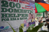 A woman stands beside a sign about hiring domestic helpers for the Mideast outside an office in Manila, Philippines on Thursday, Oct. 21, 2021. The Philippines, a leading source of global labor, has fought with alarm the spike in the number of Facebook pages, which have been used for illegal job recruitment and human trafficking in the last two years. Facebook suggested a pilot program to begin in 2021 that targeted Filipinas with pop-up messages and banner ads warning them about the dangers working overseas can pose. (AP Photo/Aaron Favila)