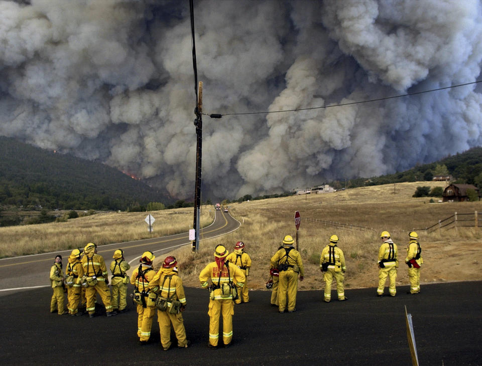 FILE - This file photo taken by Associated Press photographer Leonard Ignelzi shows firefighters watch a monstrous cloud of smoke approach as a wall of flames climbs the mountains in Oct. 28, 2003, in the Lake Cuyamaca area of Julian, Calif. Ignelzi, whose knack for being in the right place at the right time produced breathtaking images of Hall of Fame sports figures, life along the U.S.-Mexico border, devastating wildfires and numerous other major news events over nearly four decades as a photographer for The Associated Press in San Diego, has died on Friday, April 29, 2022. He was 74. (AP Photo/Lenny Ignelzi, file)