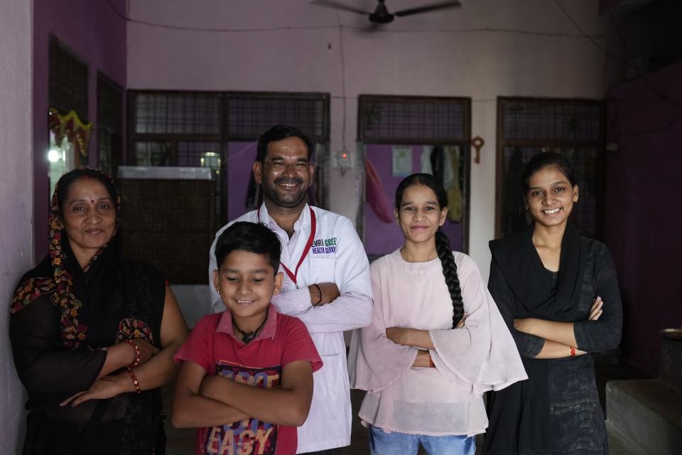 Sunil Kumar Naik, an ambulance driver, poses for a photograph with his family including his wife Sunita, left, son Lucky, daughters Sonia, second right, and Mona, at their house in Banpur in the Indian state of Uttar Pradesh, Sunday, June 18, 2023. Ambulance drivers and other healthcare workers in rural India are the first line of care for those affected by extreme heat. (AP Photo/Rajesh Kumar Singh)