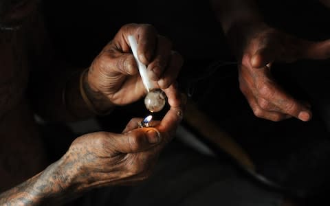 Gang members prepare a crystal meth lolly for smoking. The "tik" epidemic in the Western Cape has been blamed for a violent crime wave that has claimed thousands of lives - Credit: Brenton Geach/The Telegraph