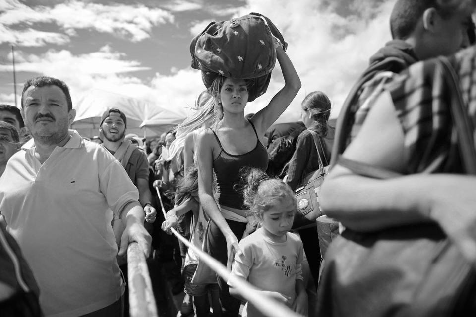 HOLD FOR DARIO LOPEZ -In this Sunday, July 17, 2016 photo, a woman carrying a bundle on her head waits in line to cross the border into Colombia through the Simon Bolivar bridge in San Antonio del Tachira, Venezuela. (AP Photo/Ariana Cubillos)