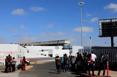 People wait to apply for asylum in the United States outside the El Chaparral border in Tijuana