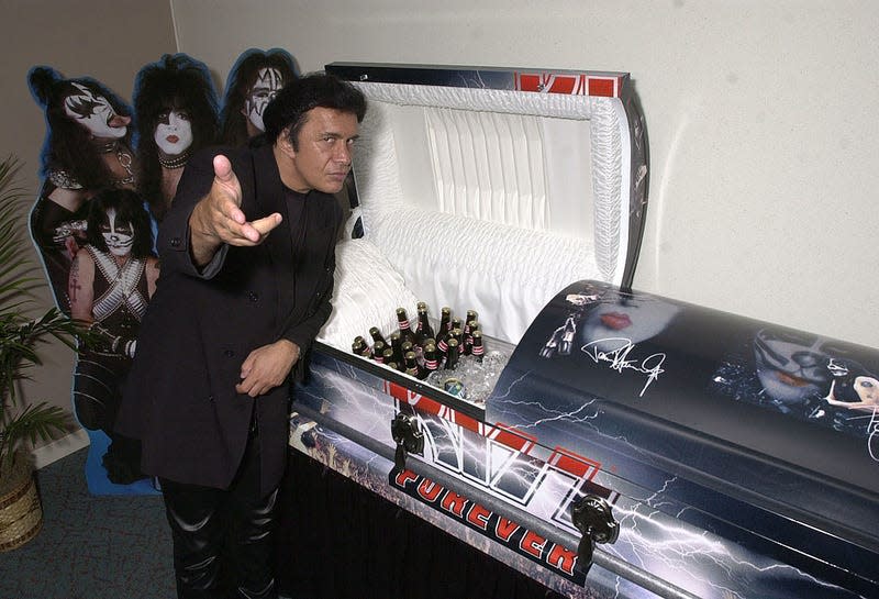 Gene Simmons poses in front of a KISS Kasket