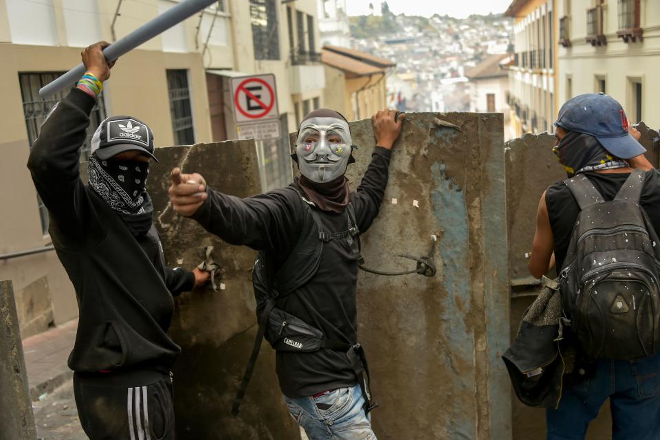 Demonstrators protect themselves with makeshift shields during clashes with riot police in Quito, as thousands march against Ecuadorean President Lenin Moreno's decision to slash fuel subsidies, on Oct. 9, 2019. (Photo: Rodrigo Buendia/AFP via Getty Images)