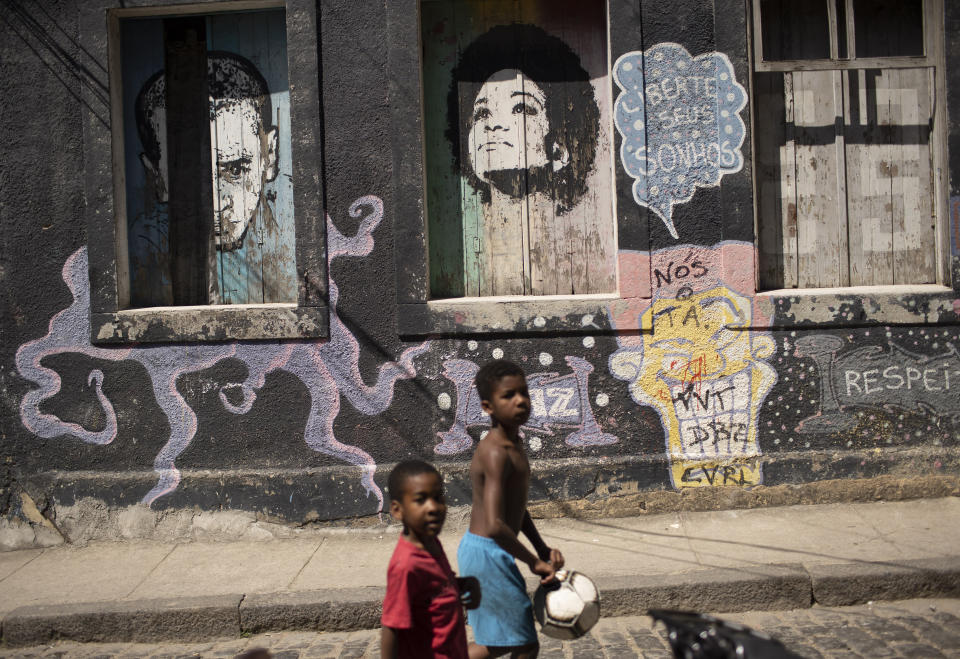 Children walk past a mural that reads "Free you dreams" amid the new coronavirus pandemic at Morro da Providencia favela, Rio de Janeiro, Brazil, Thursday, Sept. 3, 2020. Rio de Janeiro is deploying a program to administer 20 thousand COVID-19 quick tests in the city's poor neighborhoods to track the progress of the disease. (AP Photo/Silvia Izquierdo)