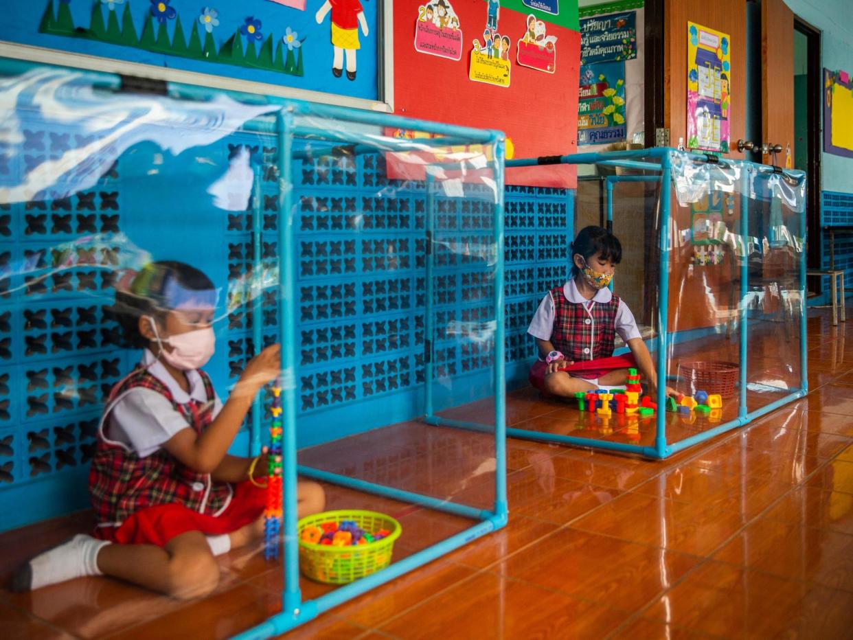 Two Thai pupils play behind plastic screens in separate play areas at the Wat Khlong Toey School on August 10, 2020 in Bangkok, Thailand: Lauren DeCicca/Getty Images