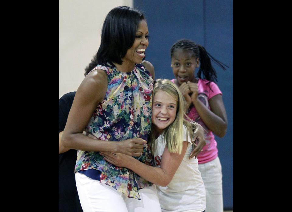 First lady Michelle Obama, left, gets a hug from Savannah Southerland during a children's fitness class on a suprise visit to the Blanchard Park YMCA, Tuesday, July 10, 2012, in Orlando, Fla.