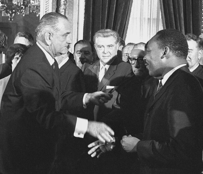 FILE - President Lyndon B. Johnson shakes hands with Martin Luther King Jr., after presenting a pen to the civil rights leader after Johnson signed the voting rights bill at the Capitol in Washington, Aug. 6, 1965. At center is Rep. Ray Madden, D-Ind. Joel Finkelstein was an accidental witness to one of the seminal events during the Civil Rights Movement, the signing in 1965 of the Voting Rights Act. He was a year out of law school when he received the call to head to the U.S. Capitol for the signing. He had helped write the law as a lawyer in the Justice Department's Civil Rights Division. (AP Photo)