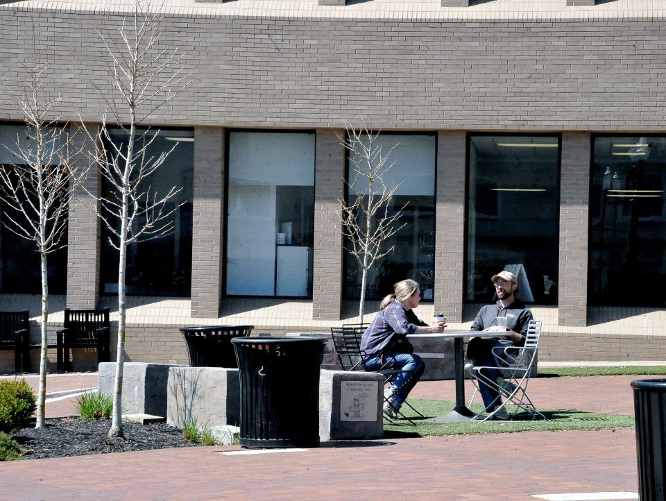 Maggie Barker-Beltran and Nathan Quinn take advantage of Monday's warm weather to talk business at one of the tables on the southwest quadrant of the square in Wooster on Monday.