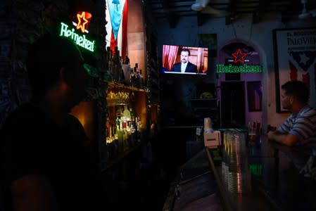People watch a television broadcast of Puerto Rico's governor Ricardo Rossello's speech at a bar in San Juan