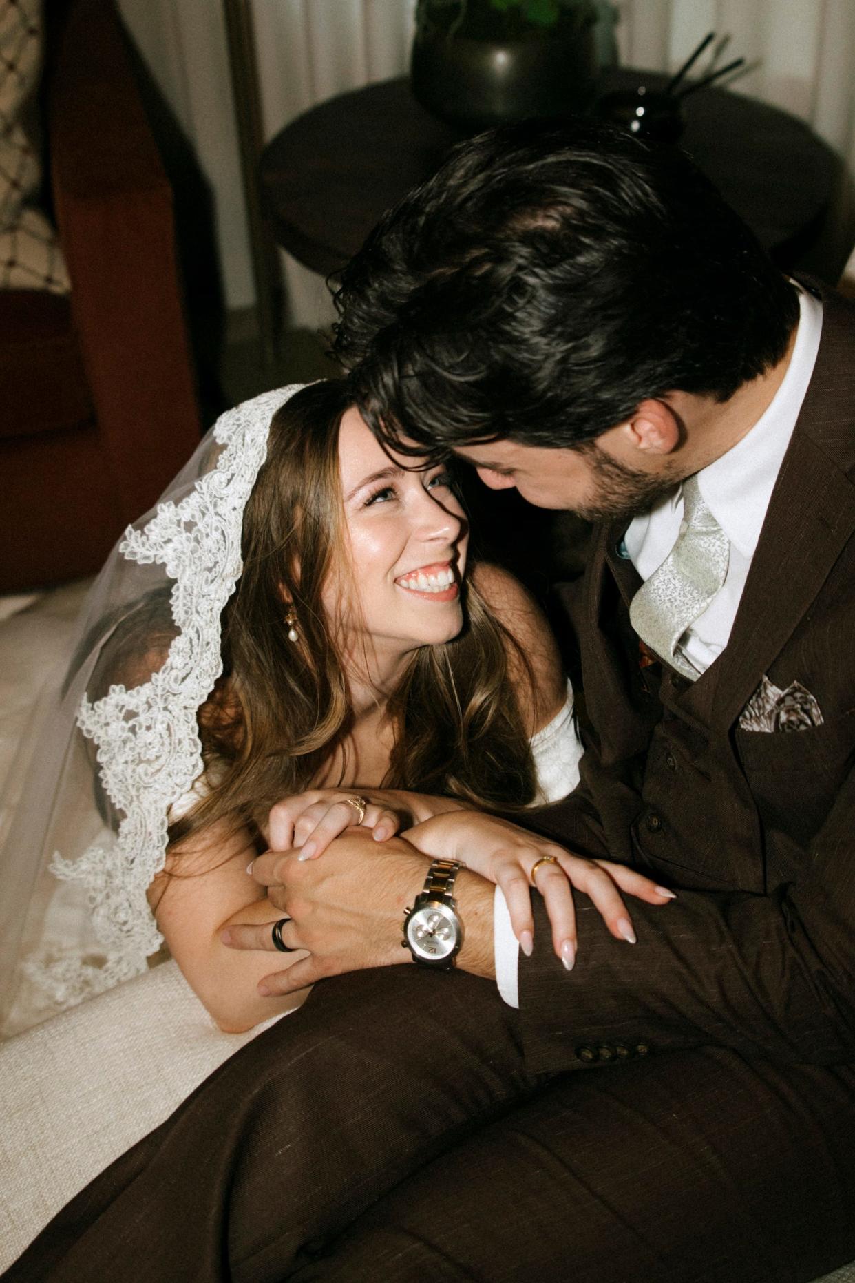 A bride and groom smile at each other in a close-up photo from their wedding.