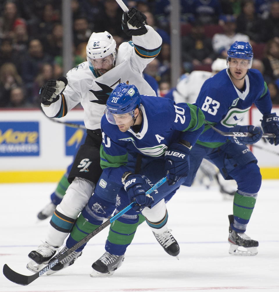 Vancouver Canucks center Brandon Sutter (20) fights for control of the puck with San Jose Sharks defenseman Erik Karlsson (65) during the second period of an NHL hockey game Saturday, Jan. 18, 2020, in Vancouver, British Columbia. (Jonathan Hayward/The Canadian Press via AP)