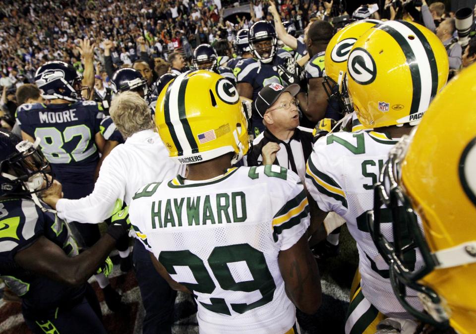 Officials try to sort out the final play of an NFL football game between the Green Bay Packers and the Seattle Seahawks as players and coaches swarm the field, Monday, Sept. 24, 2012, in Seattle. After a period of confusion, a Seahawks touchdown by wide receiver Golden Tate was allowed to stand for a 14-12 win. (AP Photo/Ted S. Warren)