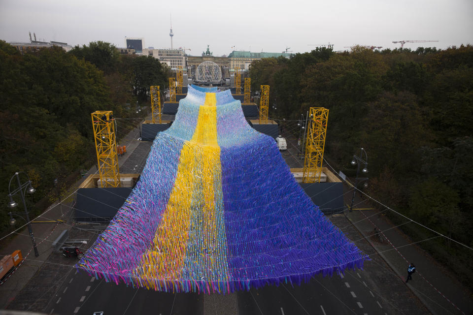 The skynet artwork 'Visions In Motion', overhangs the 'Strasse des 17. Juni' (Street of June 17) boulevard in front of the Brandenburg Gate in Berlin, Germany, Friday, Nov. 1, 2019. The art work by Patrick Shearn was made with about 100.000 streamers with written messages and is part of the celebrations marking the 30th anniversary of the fall of the Berlin Wall on Nov 9, 2019. (AP Photo/Markus Schreiber)