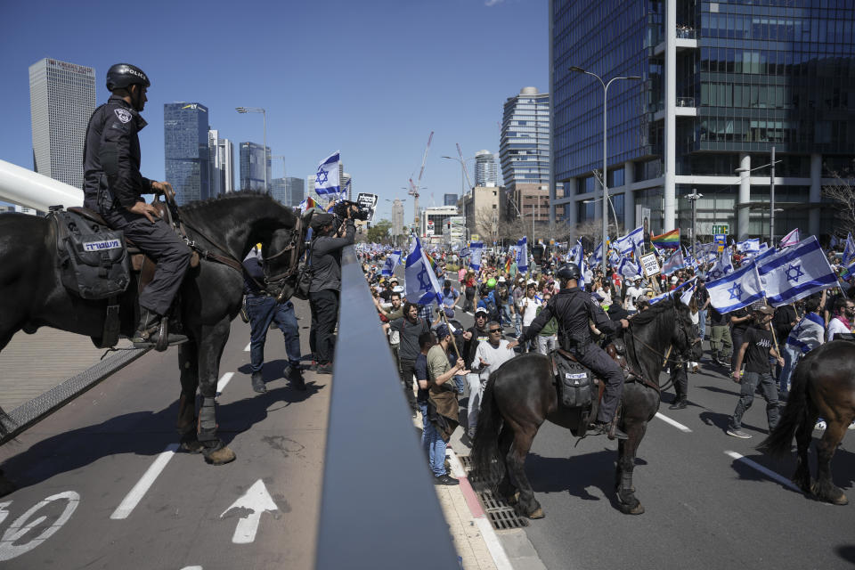 Israelis mounted policemen block protesters against plans by Prime Minister Benjamin Netanyahu's new government to overhaul the judicial system from approaching to the main freeway in Tel Aviv, Israel, Thursday, March 16, 2023. (AP Photo/Oded Balilty)