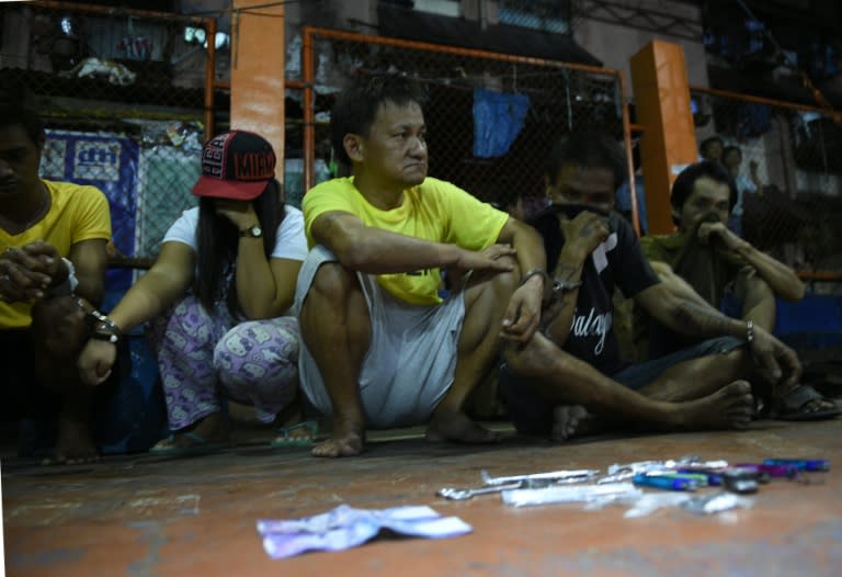 Suspected drug pushers and users sit in handcuffs next to paraphernalia confiscated during a police operation in Manila on September 30, 2016