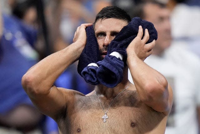 Novak Djokovic puts a towel on his head