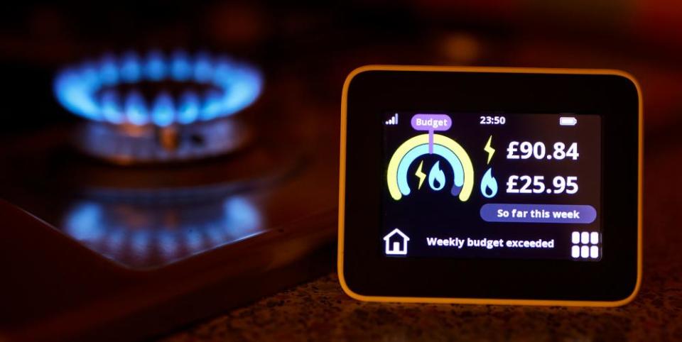 A domestic energy smart meter measuring gas and electricity usage in a home near a gas ring