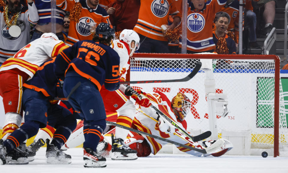 Calgary Flames goalie Jacob Markstrom, right, dives for the puck as Edmonton Oilers winger Kailer Yamamoto races for it during the first period of an NHL hockey Stanley Cup second-round playoff series game in Edmonton, Alberta, Sunday, May 22, 2022. (Jeff McIntosh/The Canadian Press via AP)