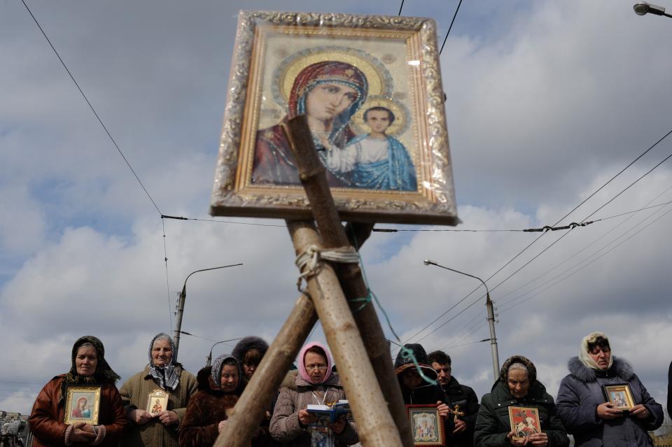 Women pray for peace near the Ukrainian regional administration building that was seized by pro-Russian activists in the eastern Ukrainian town of Slovyansk, Ukraine, Monday, April 14, 2014. Over the past 10 days, more than a dozen government buildings have been seized by angry mobs in eastern Ukraine. In several cases, assaults have been led by automatic rifle-toting men in military fatigues claiming to be seeking autonomy for the Russian-speaking east. (AP Photo/Evgeniy Maloletka)