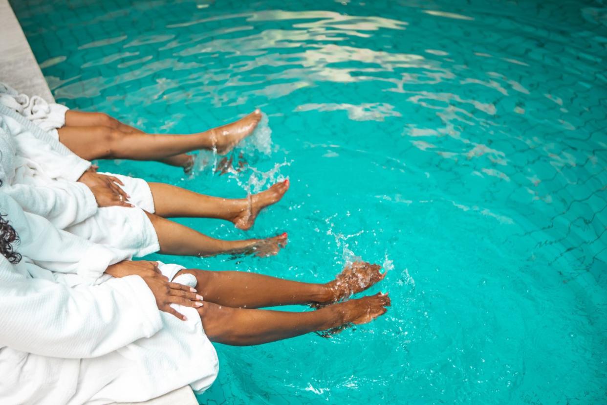 three women dipping their feet in a pool