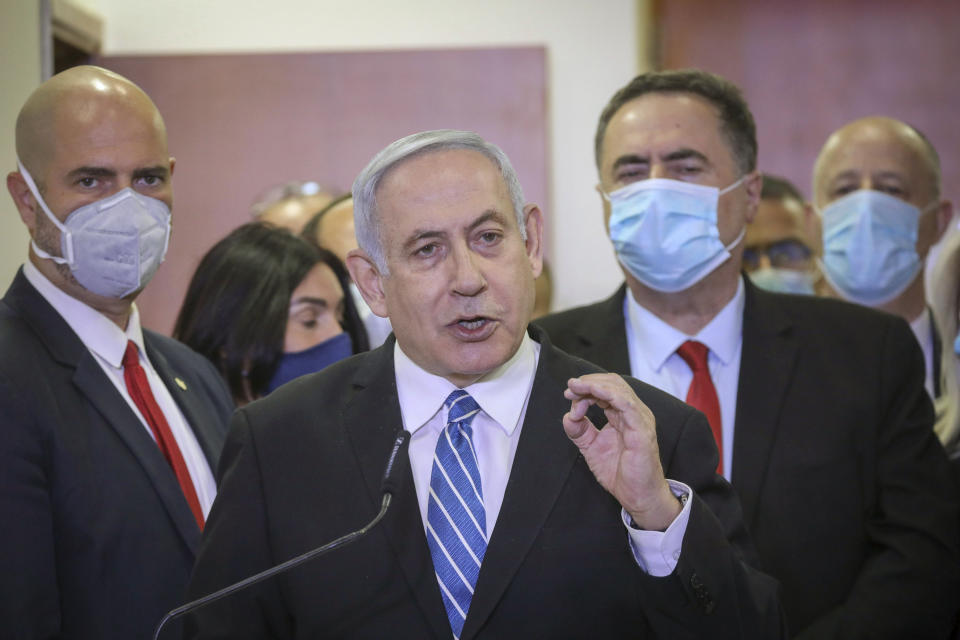 POOL - In this Sunday, May 24, 2020 photo, Israeli Prime Minister Benjamin Netanyahu accompanied by members of his Likud Party in masks delivers a statement before entering the district court in Jerusalem. Netanyahu's fulminating tirade against Israel's legal system on the steps of a Jerusalem courthouse managed to even overshadow the opening of his historic corruption trial. Surrounded by loyal deputies, and with hundreds of impassioned supporters cheering him outside and echoing his charges, Netanyahu's onslaught capped a years-long campaign that has bitterly divided the country and raised fears of irreparably tearing apart the delicate fabric of Israeli society. (AP Photo/Yonatan Sindel/Pool Photo via AP)