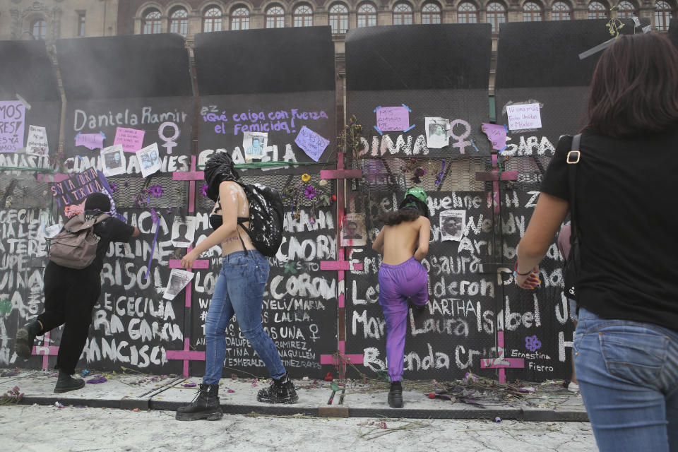 Demonstrators strike a barricade that is protecting the National Palace during a march to commemorate International Women's Day and protest against gender violence, in Mexico City, Monday, March 8, 2021. (AP Photo/Ginnette Riquelme)