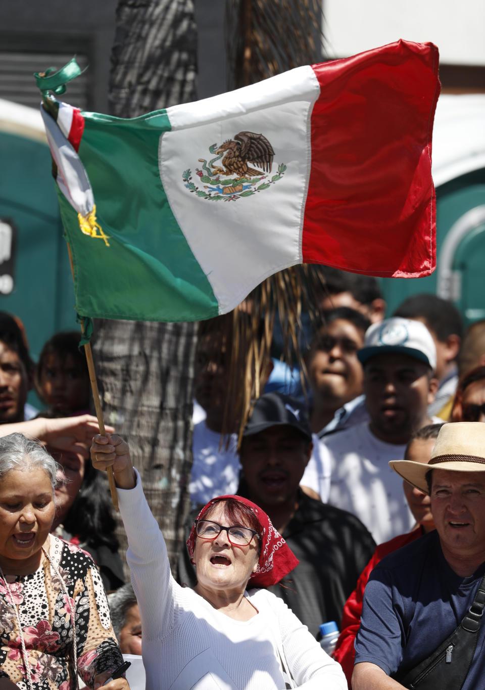 A woman waves a Mexican flag prior to the speech by Mexican President Andres Manuel Lopez Obrador at a rally in Tijuana, Mexico, Saturday, June 8, 2019. Mexican President Andres Manuel Lopez Obrador will hold the rally in Tijuana even as President Trump has put on hold his plan to begin imposing tariffs on Mexico on Monday, saying the U.S. ally will take "strong measures" to reduce the flow of Central American migrants into the United States. (AP Photo/Eduardo Verdugo)