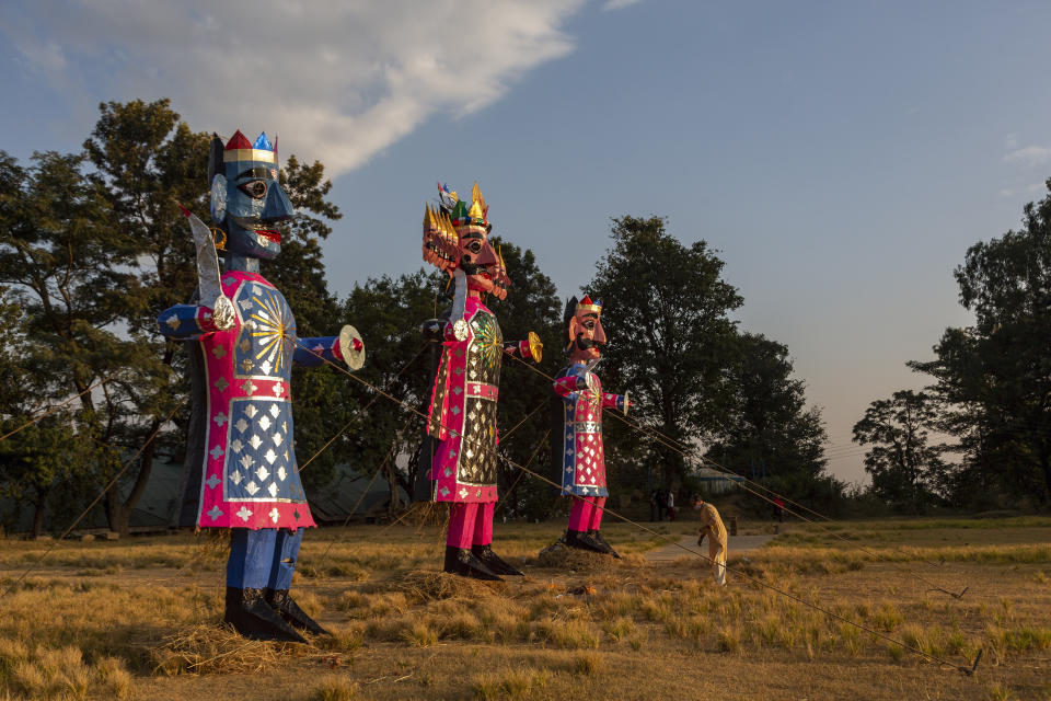 A priest gets ready to conduct prayers next to the effigies of mythological demon king Ravana and his kins during Dussehra festival celebrations toned down due to the coronavirus pandemic in Dharmsala, India, Sunday, Oct. 25, 2020. The Hindu festival season is traditionally laced with an unmatched fanfare and extravaganza, with socializing being the hallmark of the celebration. But this year's festivities have started on a pale note. (AP Photo/Ashwini Bhatia)