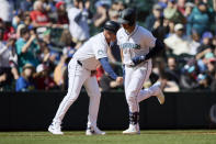 Seattle Mariners designated hitter Mitch Garver is congratulated by third base coach Manny Acta as he rounds the bases after hitting a solo home run off a pitch fromCincinnati Reds pitcher Andrew Abbott during the sixth inning of a baseball game, Wednesday, April 17, 2024, in Seattle. (AP Photo/John Froschauer)