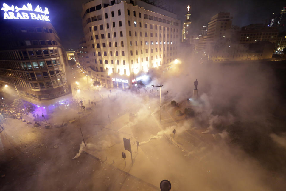 FILE - In this Friday, Oct. 18, 2019 file photo, Lebanese riot police fire tear gas during a protest against government's plans to impose new taxes in Beirut, Lebanon. A year ago, hundreds of thousands of Lebanese took to the streets in protests nationwide that raised hopes among many for a change in a political elite that over that decades has run the country into the ground. (AP Photo/Hassan Ammar, File)