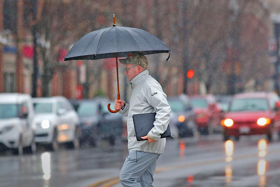 Under cover, a n uses an umbrella to keep off the cold rain in Quincy Square on Tuesday January 3, 2023.