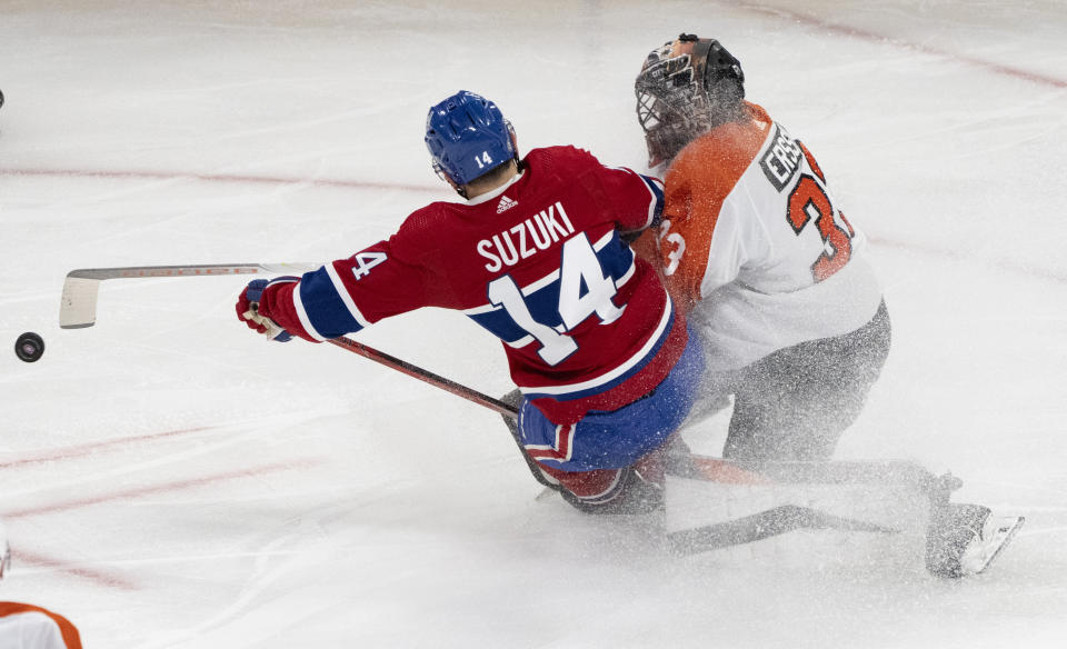 Montreal Canadiens' Nick Suzuki (14) collides with Philadelphia Flyers goaltender Samuel Ersson (33), who poke-checks the puck during the second period of an NHL hockey game Thursday, March 28, 2024, in Montreal. (Christinne Muschi/The Canadian Press via AP)