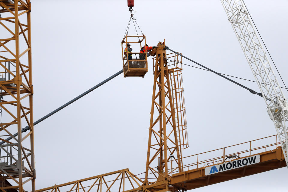 Workers in a bucket hoisted by a crane begin the process of preparing the two unstable cranes for implosion at the collapse site of the Hard Rock Hotel, which underwent a partial, major collapse while under construction last Sat., Oct., 12, in New Orleans, Friday, Oct. 18, 2019. Plans have been pushed back a day to bring down two giant, unstable construction cranes in a series of controlled explosions before they can topple onto historic New Orleans buildings, the city's fire chief said Friday, noting the risky work involved in placing explosive on the towers. (AP Photo/Gerald Herbert)