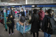 A worker directs travelers at the check-in line for a Japan Airlines flight to Tokyo at Beijing Capital International Airport in Beijing, Sunday, Jan. 15, 2023. A hoped-for boom in Chinese tourism in Asia over next week’s Lunar New Year holidays looks set to be more of a blip as most travelers opt to stay inside China if they go anywhere. (AP Photo/Mark Schiefelbein)