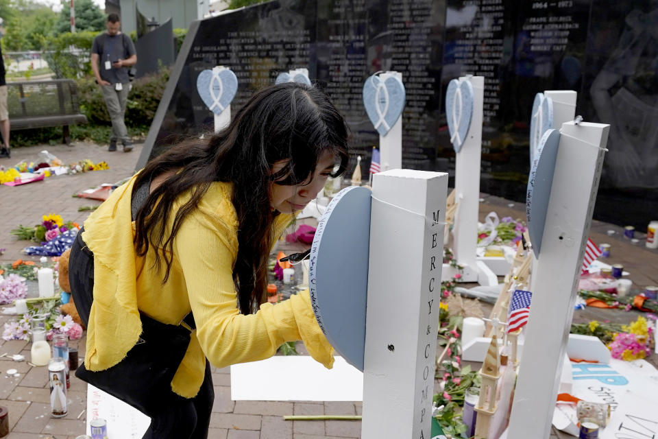 Yesenia Hernandez, granddaughter to Nicolas Toledo, who was killed during Monday's Highland Park., Ill., Fourth of July parade, writes on a memorial for Toledo along with the six others who lost their lives in the mass shooting, Wednesday, July 6, 2022, in Highland Park. (AP Photo/Charles Rex Arbogast)