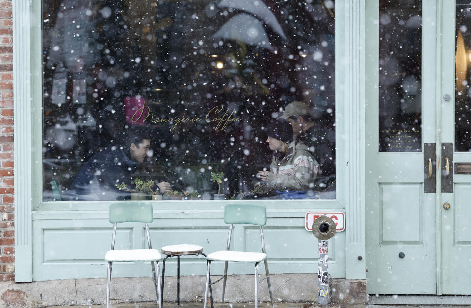 Customers sit inside a cafe as snow falls in the Old City neighborhood of Philadelphia on Friday, Jan. 19, 2024. (Yong Kim/The Philadelphia Inquirer via AP)