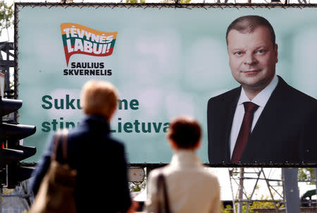 FILE PHOTO: People walk past an election campaign placard of a Lithuanian presidential candidate Saulius Skvernelis in Vilnius, Lithuania May 9, 2019. REUTERS/Ints Kalnins