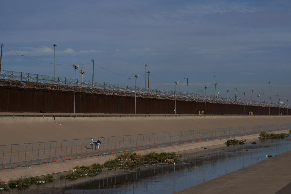 Migrantes caminan a lo largo de la frontera donde militares de la Guardia Nacional de Texas instalaron una cerca, como parte de una "fuerza fronteriza de contingencia", vista desde Ciudad Juárez, México, el martes 27 de diciembre de 2022. (Paul Ratje/The New York Times)
