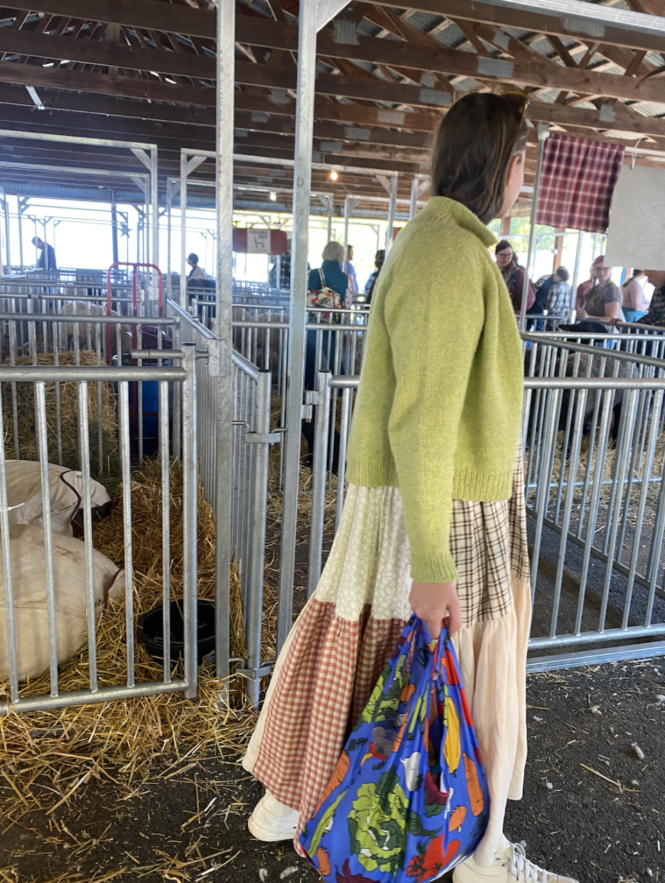 A Sheep and Wool Festival attendee in a patchwork frock, woolen citron sweater and carrying a vegetable-printed Baggu bag.