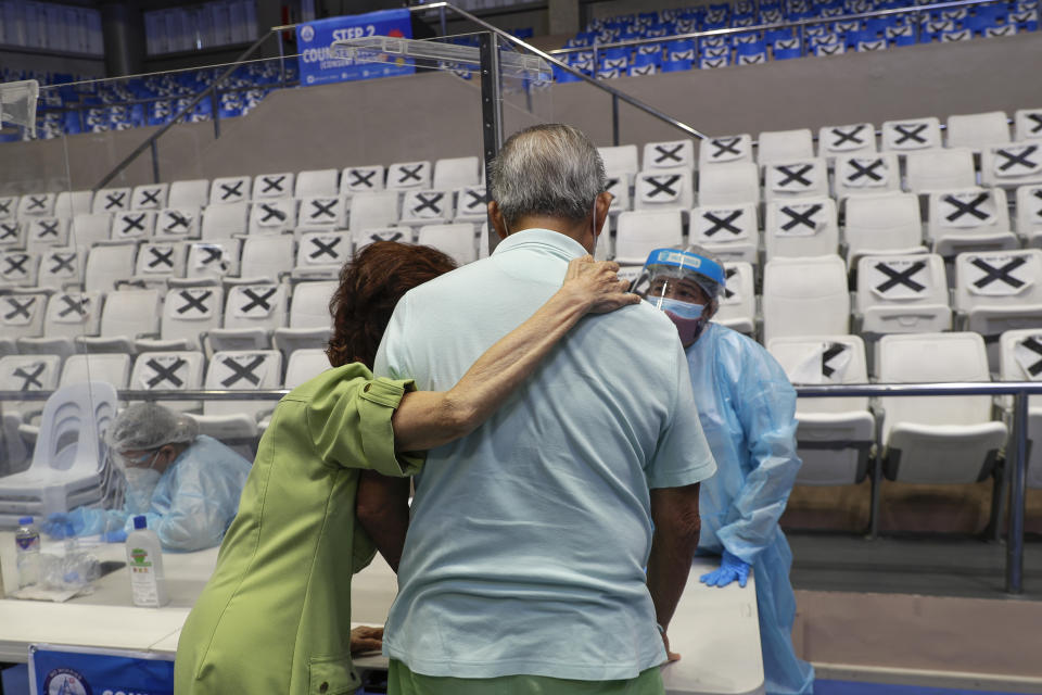 An elderly couple talks to a health worker at a vaccination center inside the Makati Coliseum in Manila, Philippines on Tuesday, May 4, 2021. The Philippines started a simultaneous vaccination of the initial 15,000 doses of Russia's Sputnik V COVID-19 vaccines that arrived in the country earlier this week. (AP Photo/Aaron Favila)