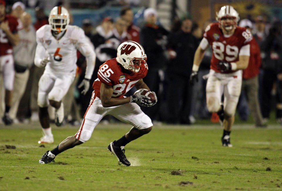 FILE - Wisconsin wide receiver David Gilreath (85) carries against Miami on a Citrus Bowl Stadium field full of divots and clumps of sand during the second half of the Champs Sports Bowl NCAA college football game in Orlando, Fla., Dec. 29, 2009. Of the 133 schools that currently compete in the top tier of the NCAA Division I, 94 have artificial surface football fields (71%) and 39 have grass (29%), most of those at Power Five schools that can afford the upkeep and maintenance.(AP Photo/John Raoux, File)